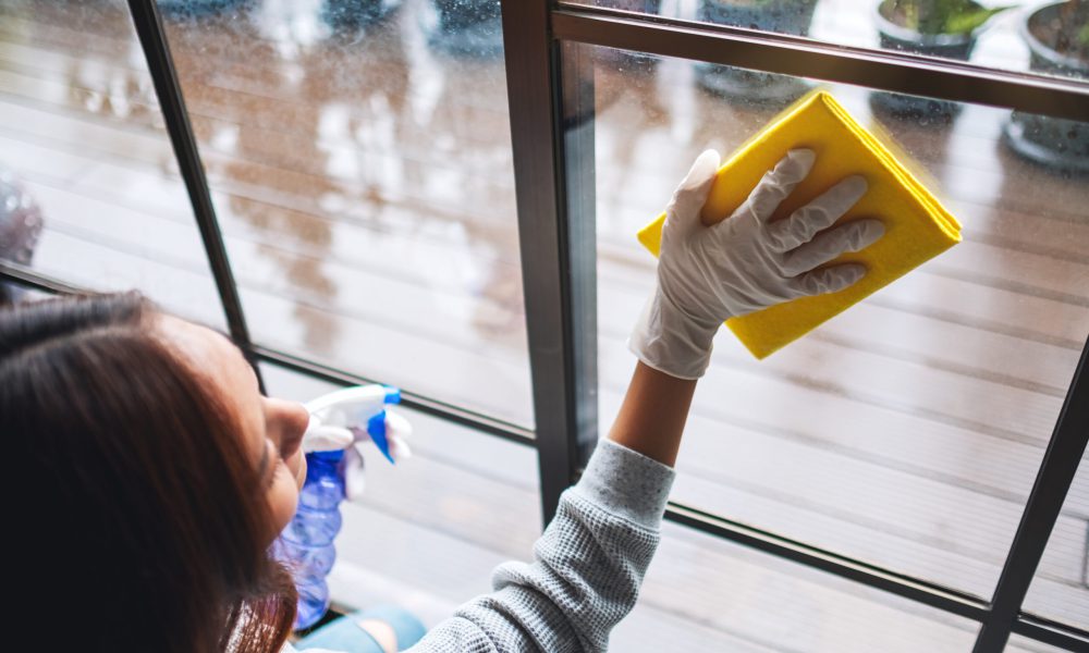 A young woman wearing protective glove cleaning the window for housework concept