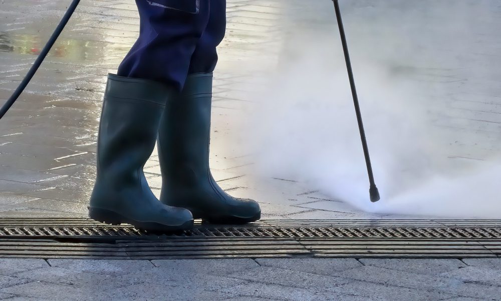 Man steam cleaning street with pressure